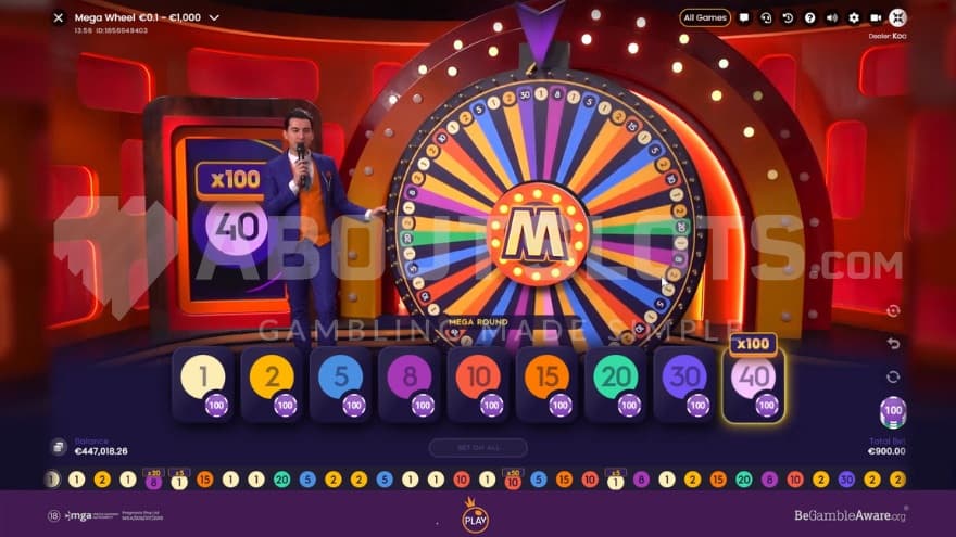 Main game with a big wheel being presented on the screen, where a game host is standing on the left side of it.
